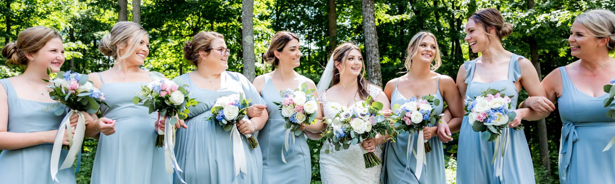 wedding party holding pink, blue and white wedding bouquets 